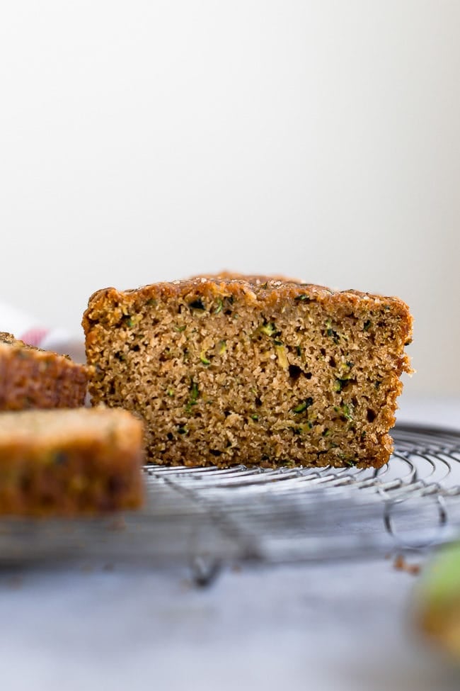 loaf of zucchini bread sliced on cooling rack. 