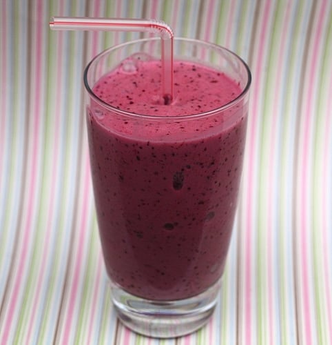 blueberry banana smoothie in glass with straw