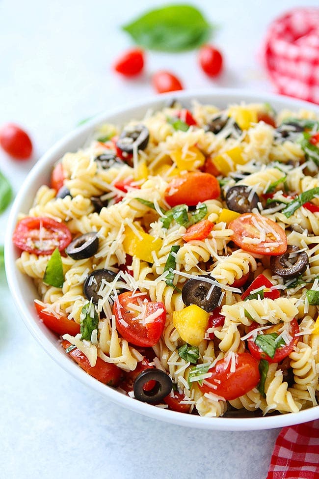 Easy Pasta Salad in bowl with veggies, basil, and Parmesan cheese