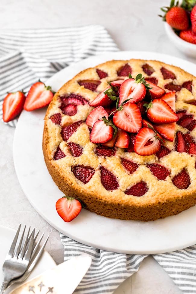 Homemade strawberry cake recipe that is SO easy to make! The perfect spring dessert! #easyrecipe #strawberry #strawberrycake #cake #dessert #spring #easydessert #buttermilk #baking strawberry cake with fresh strawberries on marble board.