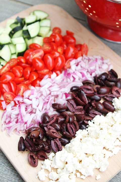 Greek Tortellini Pasta Salad Ingredients laid out on cutting board