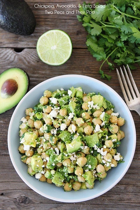 Easy Chickpea, Avocado, & Feta Salad  in blue bowl with avocado, lime, and cilantro. 