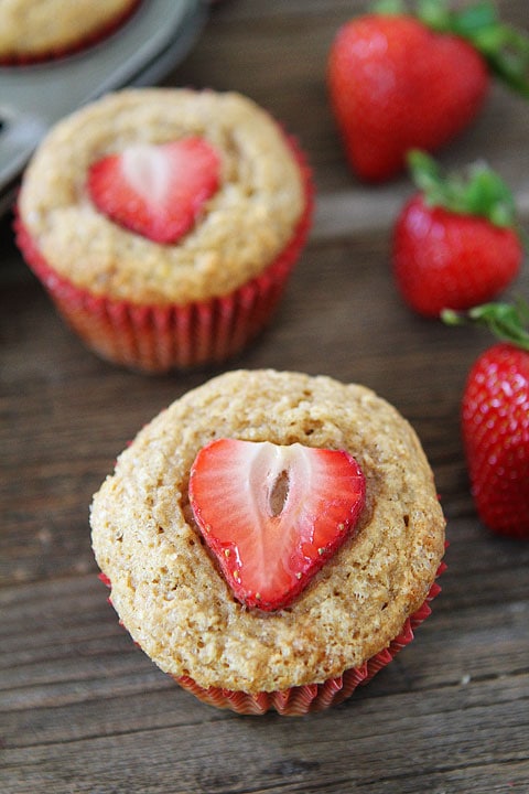 Whole Wheat Banana Muffins in red baking cups with strawberries on top