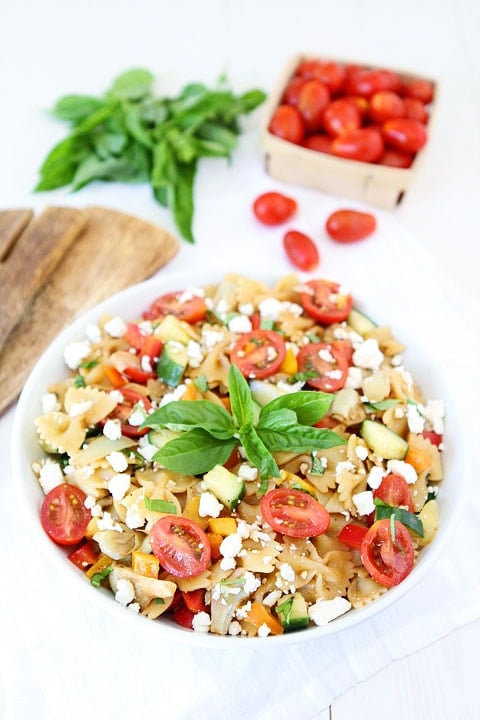 pasta salad in large serving bowl with tomatoes and fresh basil. 