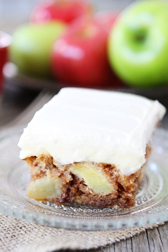 fresh apple cake with frosting on glass serving plate