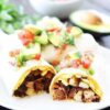 Breakfast burrito on plate topped with avocado and tomato