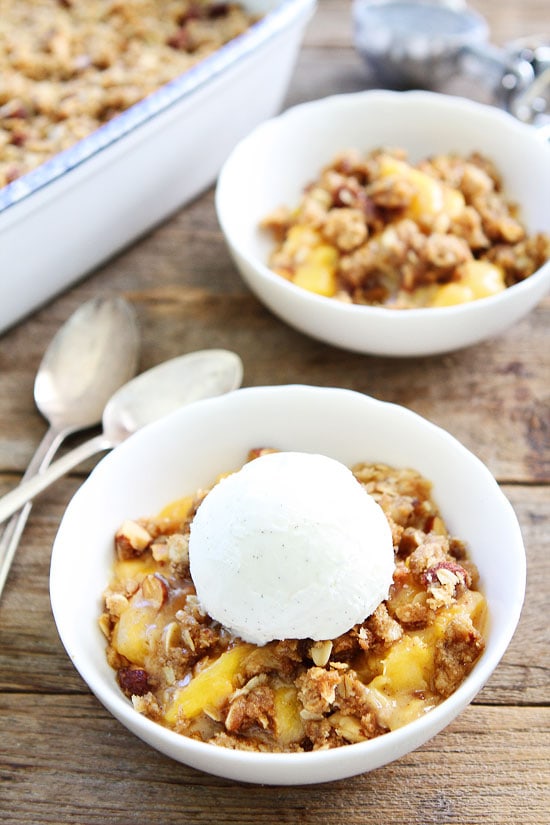 Peach Almond Crisp Recipe on twopeasandtheirpod.com Simple crisp made with fresh peaches and an almond oat topping. This easy dessert is a summertime favorite! Peach Crisp in a bowl with ice cream