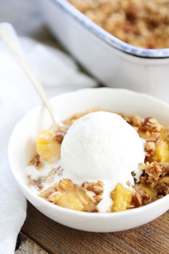 Peach Almond Crisp Recipe on twopeasandtheirpod.com Simple crisp made with fresh peaches and an almond oat topping. Top with ice cream for an extra special dessert! Peach Crisp Recipe with vanilla ice cream