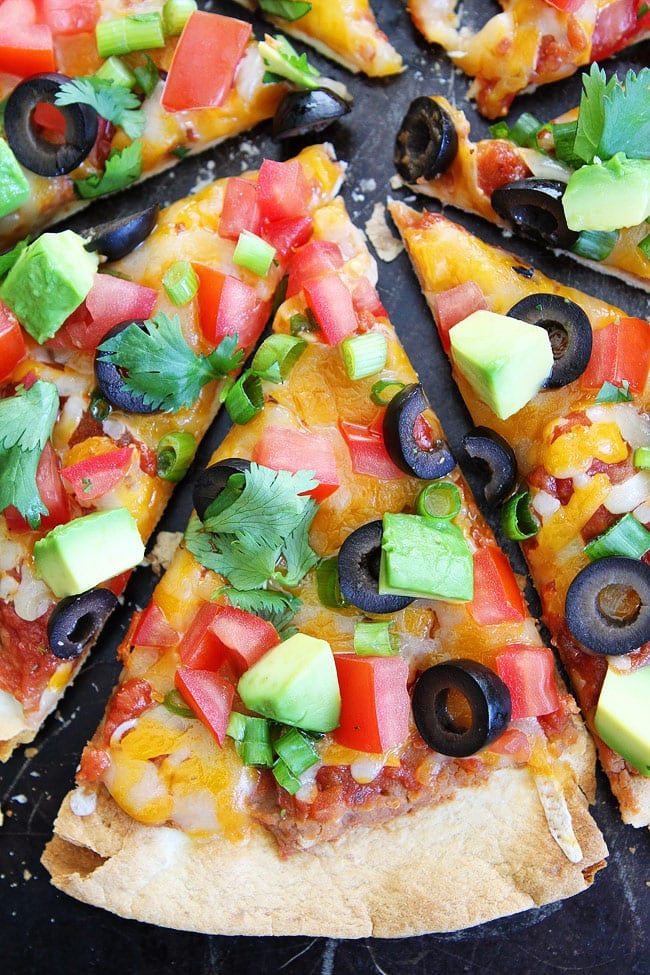 Mexican Pizza topped with cilantro, onions, avocado, tomatoes and olives