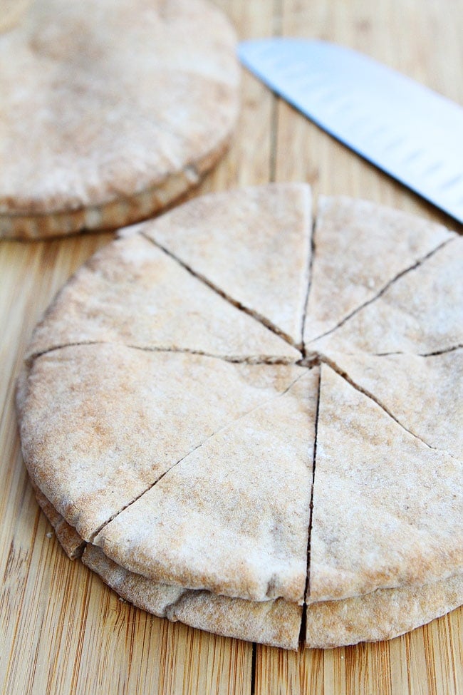 pita bread cut into triangles on wood cutting board. 