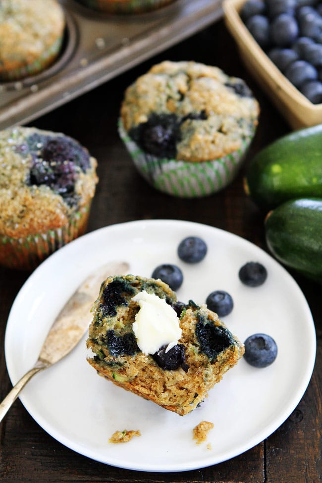 Zucchini Banana Blueberry Muffin with butter on plate.