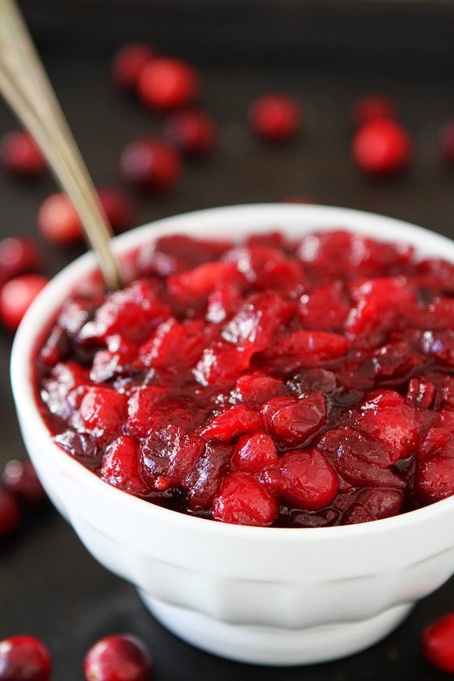 Maple Cranberry Sauce Recipe-Fresh cranberry sauce sweetened with pure maple syrup, orange zest, orange juice, and a hint of cinnamon. This is the BEST cranberry sauce recipe! Add it to your Thanksgiving and Christmas menus. homemade cranberry sauce in bowl with spoon.