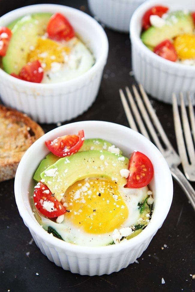 Baked Eggs with Spinach topped with avocado, tomatoes, and crumbled feta cheese