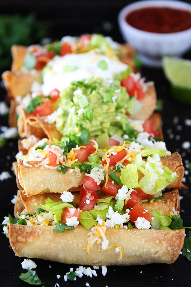 Homemade Taquitos topped with guacamole, cheese and tomato