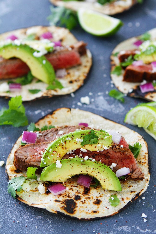 steak tacos in corn tortillas with avocado and spices.