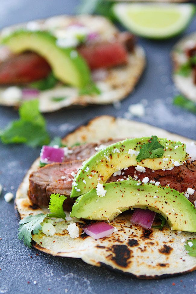 Steak tacos with avocado, cilantro, red onion, and queso fresco. 