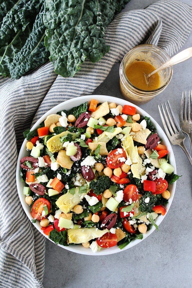 Mediterranean Kale Salad with chickpeas, tomatoes, cucumber, red pepper, artichoke hearts, olives, feta cheese, pita chips and a simple hummus dressing.