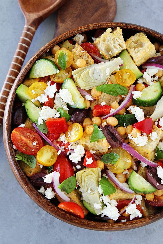 Greek Panzanella Salad made with cubes of crusty bread, tomatoes, cucumbers, chickpeas, artichoke hearts, peppers, olives, red onion, feta cheese, and a simple Greek salad dressing. 