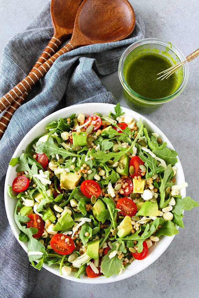 Summer Arugula Salad with couscous, avocado, corn, tomatoes, cheese, pepitas, and a simple basil vinaigrette. This fresh and easy salad is the best summer salad!