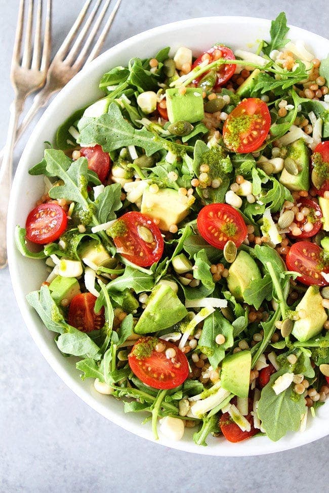 Summer Arugula Salad with couscous, avocado, corn, tomatoes, cheese, pepitas, and a simple basil vinaigrette. This fresh and easy salad goes great with any summer meal or can be your summer meal!