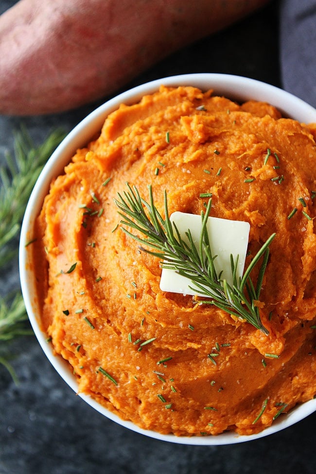 Mashed Sweet Potatoes in bowl with butter and rosemary  