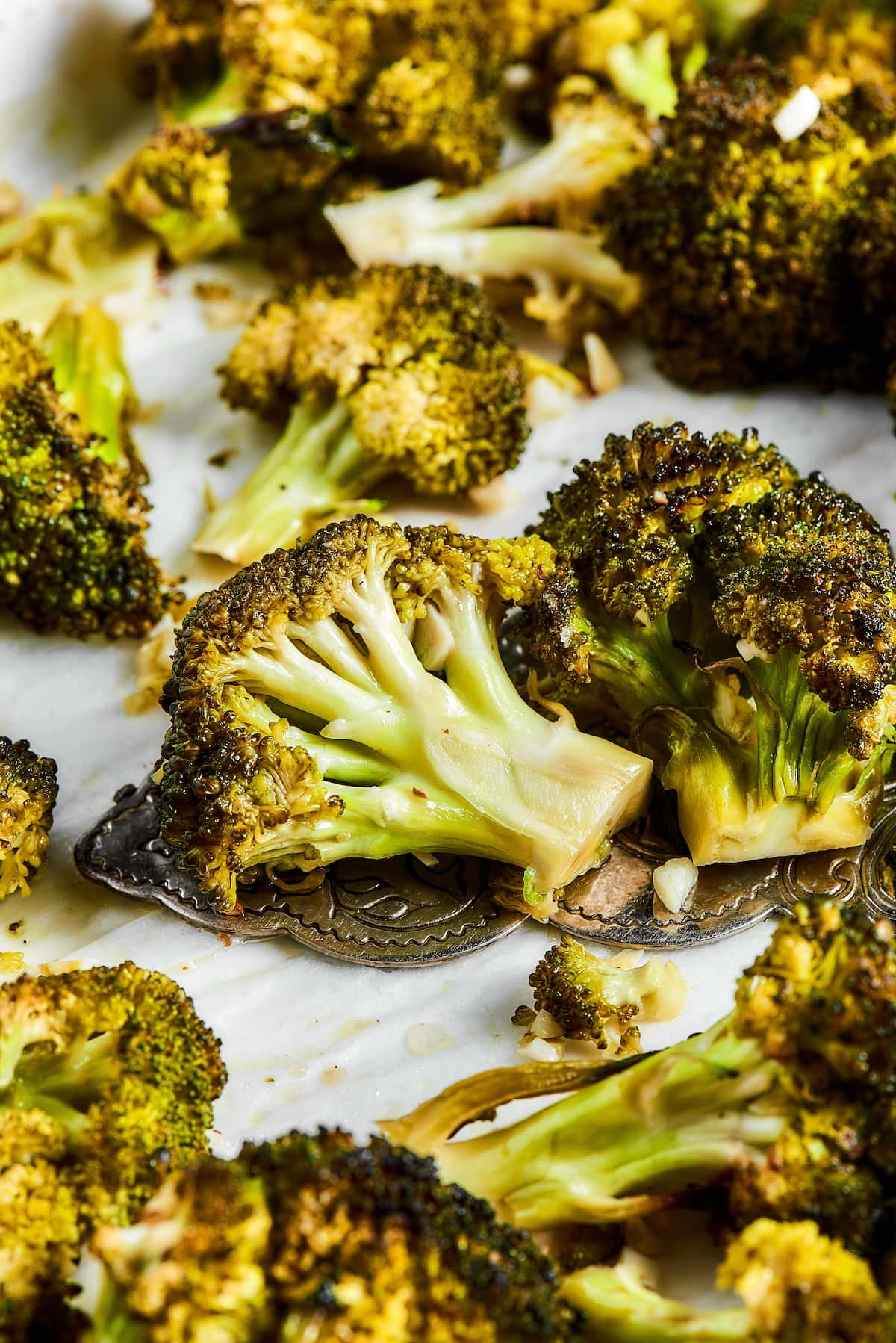 Roasted broccoli on white parchment paper.