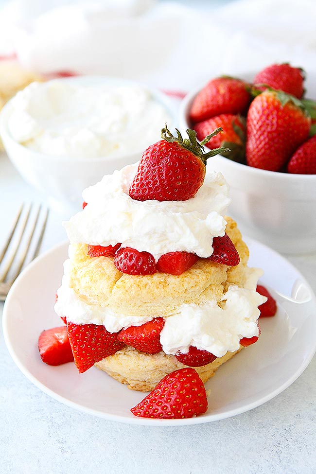 Strawberry Shortcake with bowl of whipped cream and bowl of strawberries. 