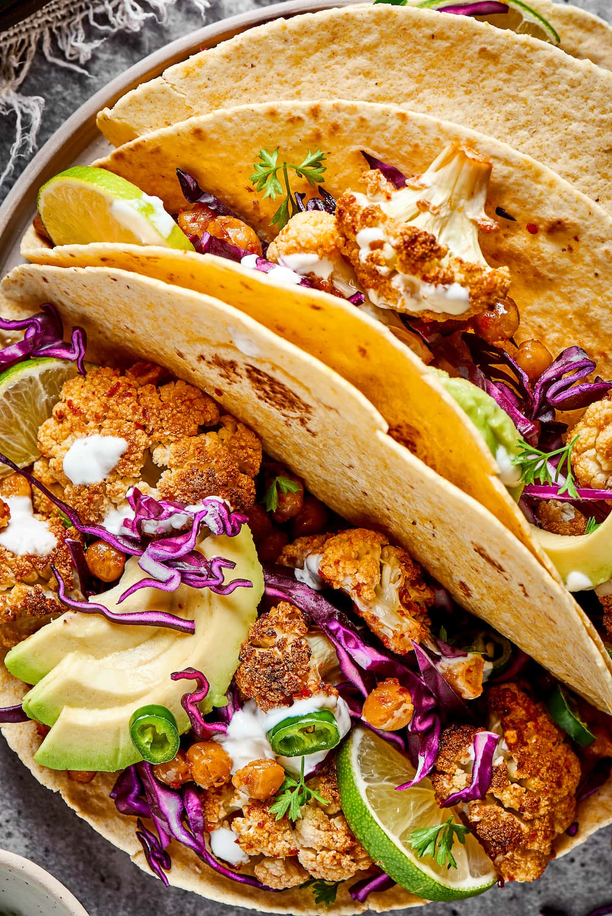 Close up of three roasted cauliflower and chickpea tacos on a plate