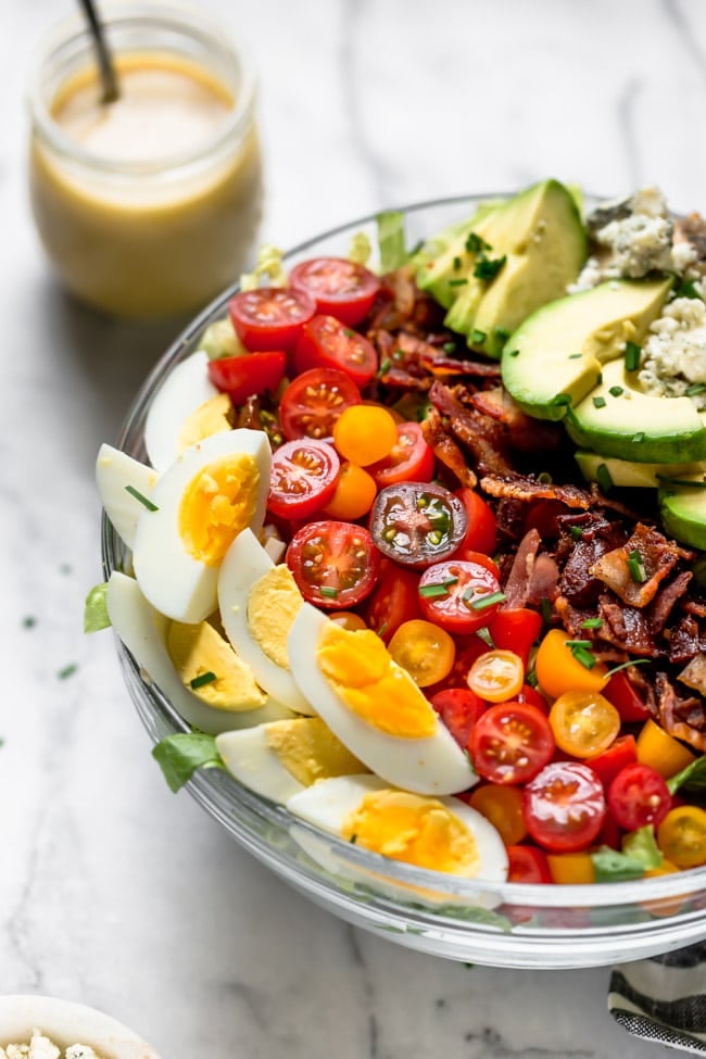 Cobb Salad in Bowl with salad dressing in jar