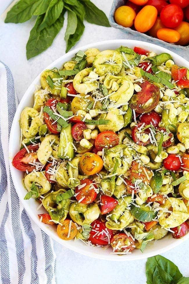 summer pasta salad in bowl with basil and tomatoes.