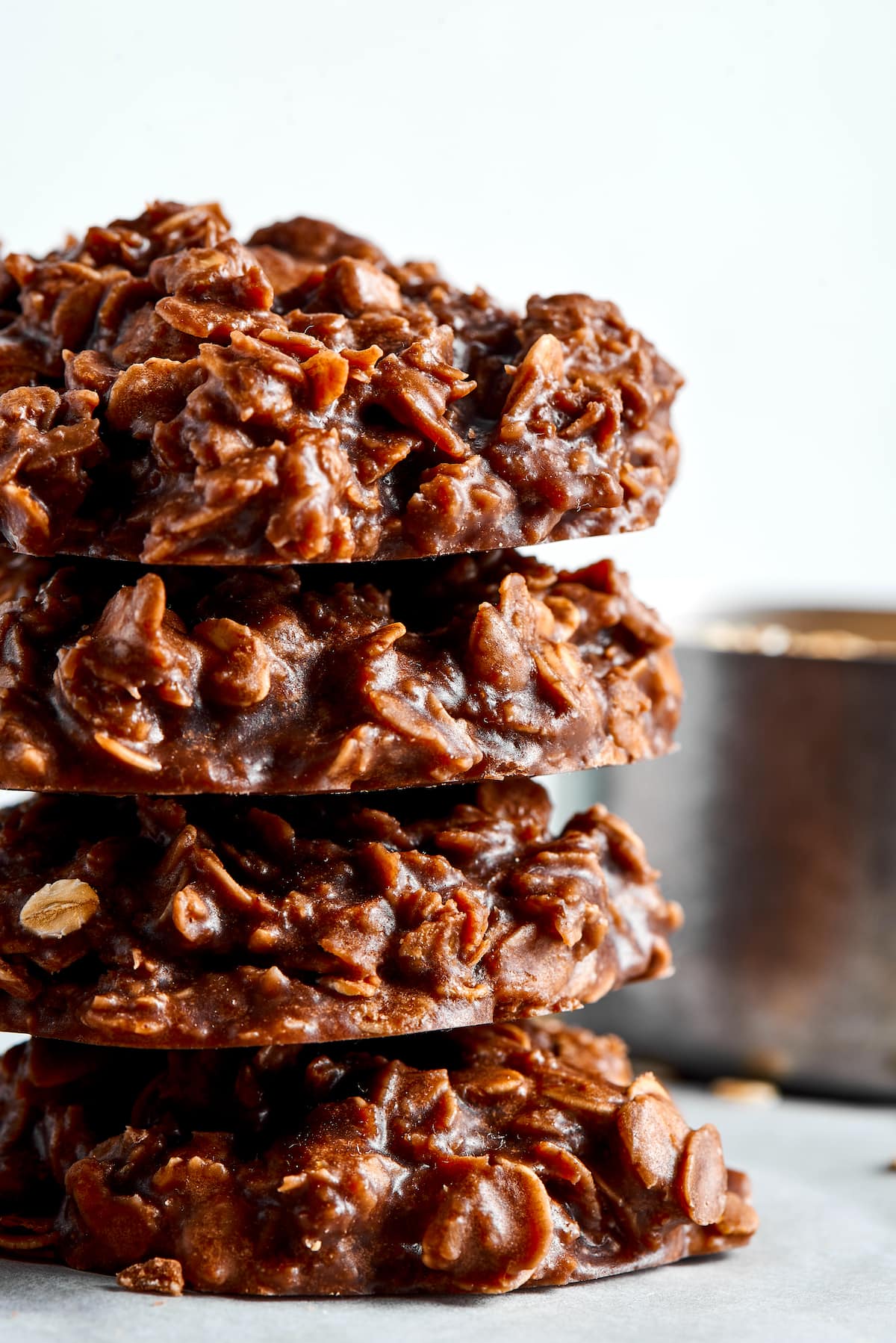 These no bake cookies are full of chocolate, peanut butter, and oatmeal, and taste just as good as normal cookies, but they're quicker! Four no bake cookies stacked on top of each other, with a saucepan in the background