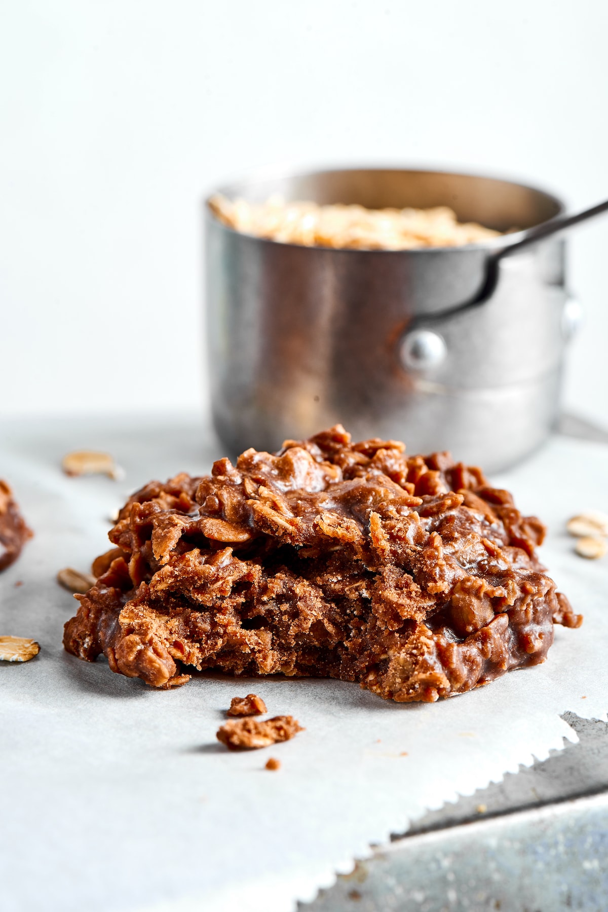 These no bake cookies are full of chocolate, peanut butter, and oatmeal, and taste just as good as normal cookies, but they're quicker! A no bake cookie with a bite taken out of it, with a saucepan in the background