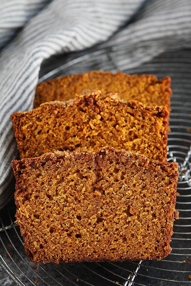 This Is The PERFECT Pumpkin Bread Recipe, It Is Moist, Perfectly Spiced, And Easy To Make. It Will Become One Of Your Favorite Fall Recipes! #pumpkin #bread #pumpkinbread #fall #recipe #easyrecipe #baking #pumpkinrecipe pumpkin bread slices on cooling rack with towel.