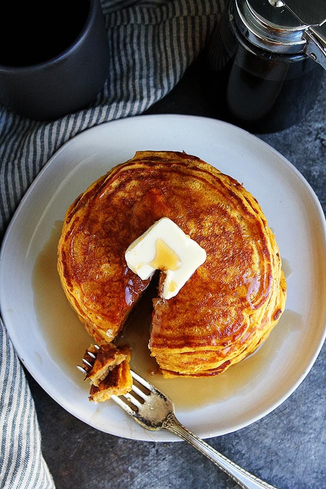 These Fluffy Pumpkin Pancakes Are Sweet, Satisfying, And Easy To Make. Enjoy A Stack For Breakfast, They Are A Fall Favorite! #pumpkin #pancakes #breakfast #fall #pumpkinpancakes #brunch #easyrecipe #recipe #vegetarian Pumpkin Pancakes on plate with butter and maple syrup.
