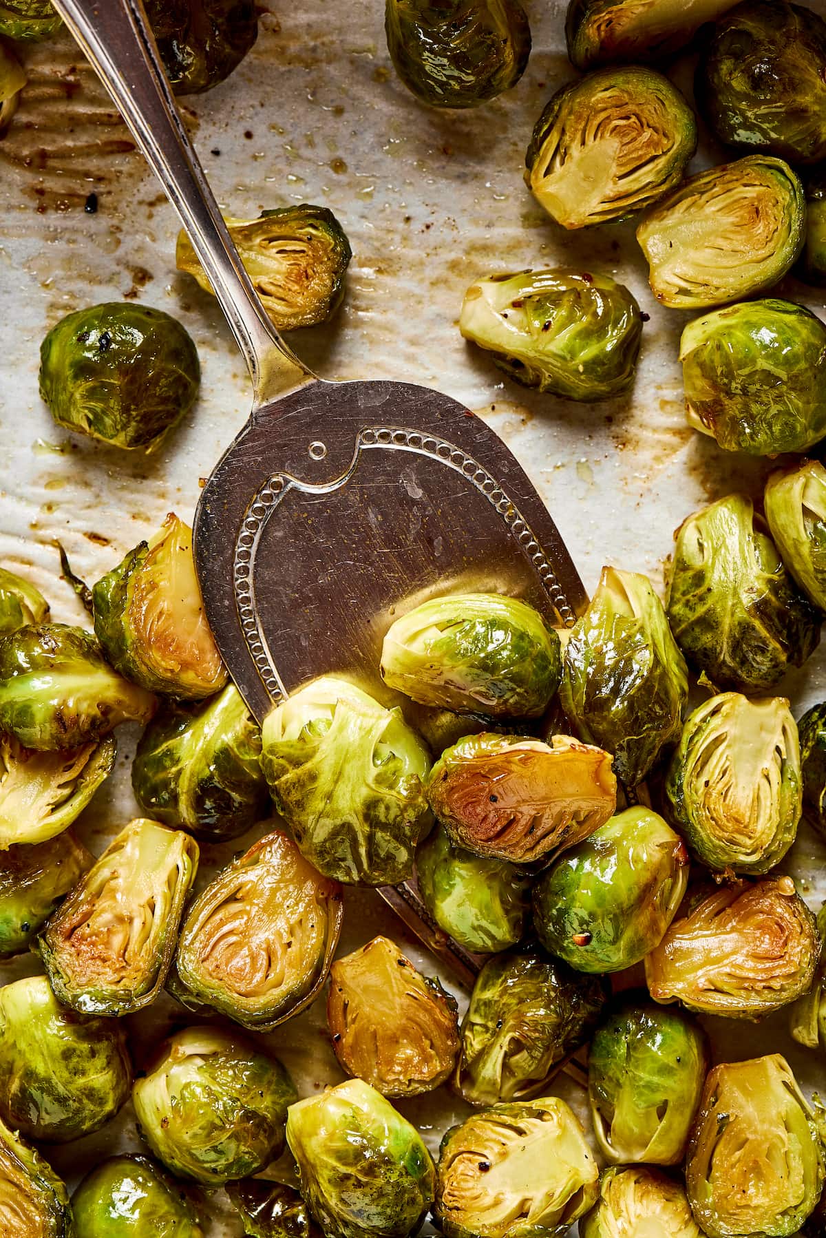 Close up of a serving spoon scooping some roasted Brussels sprouts