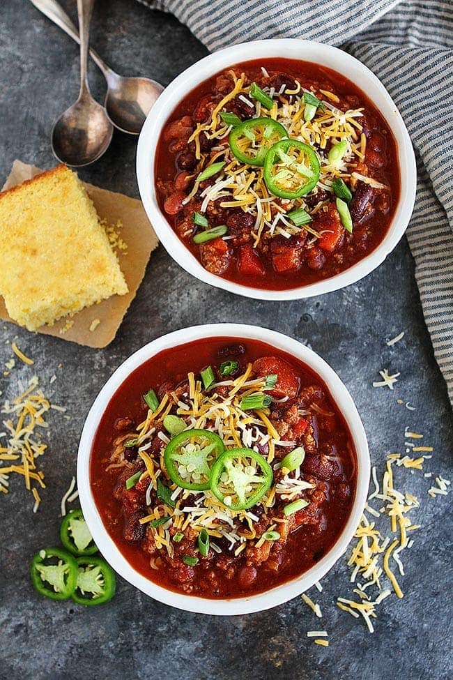 This easy Slow Cooker Beef Chili is a family favorite! Get out the crockpot and make it for dinner today! #chili #slowcooker #crockpot #dinner #easyrecipe #chilirecipe #fall #winter #gameday #glutenfree beef chili in bowls with toppings.