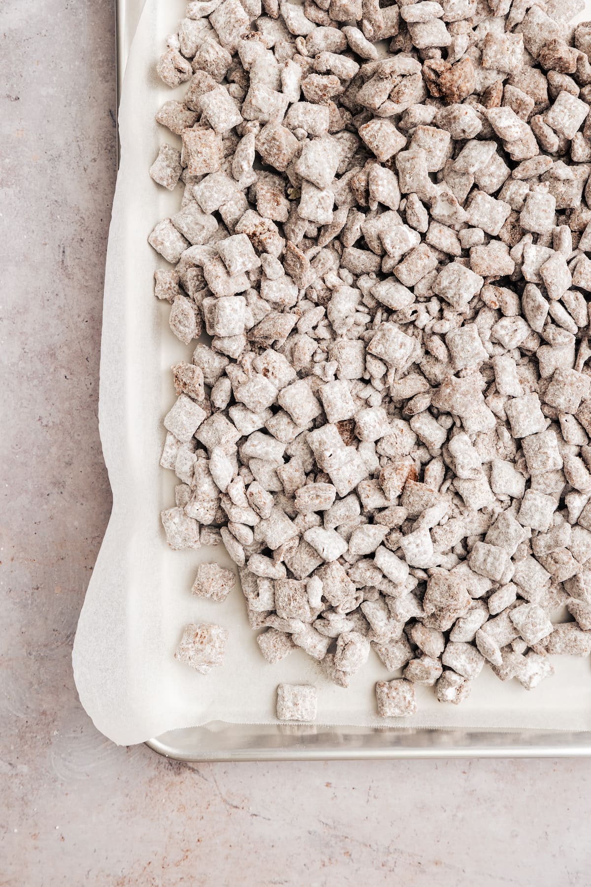 Overhead view of puppy chow on a parchment-lined baking sheet.