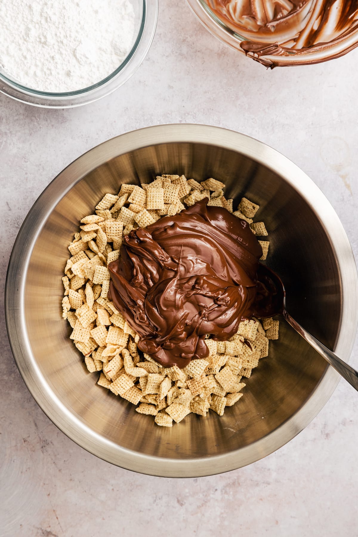 The chocolate peanut butter mixture is added into a large bowl with Chex cereal.