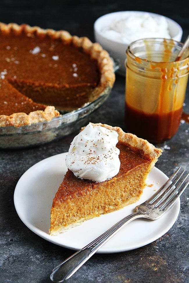 Piece of Salted Caramel Pumpkin Pie on plate with whipped cream and a fork.