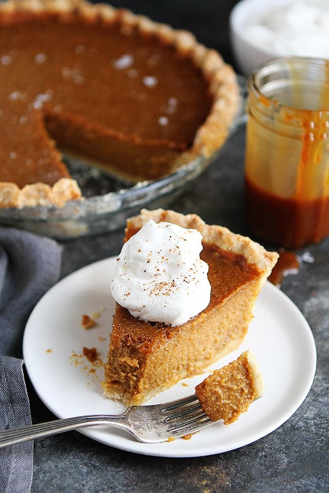 Salted caramel pumpkin pie on plate with a bite taken out of it with a fork. 