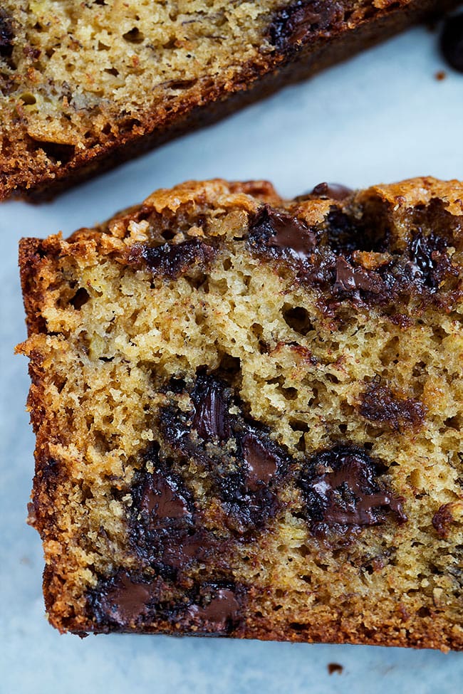 This moist and easy chocolate chip banana bread recipe is soft, fluffy, has gooey chocolate chips, and is the perfect way to use up bananas. Close up of a slice of chocolate chip banana bread with melted chocolate chips.
