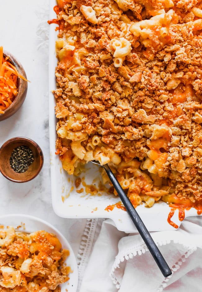 baked mac and cheese with cracker topping in pan with spoon. 