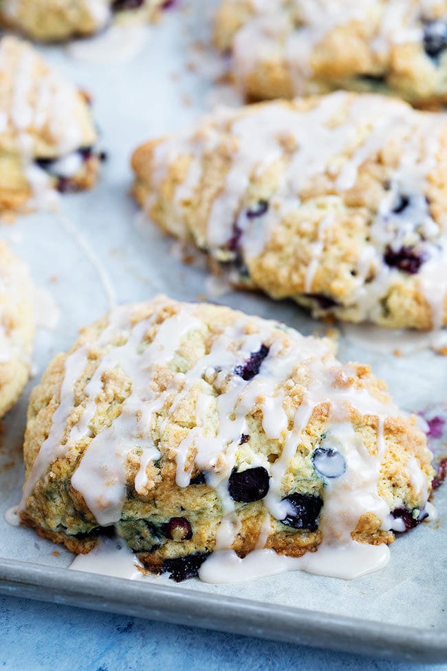 blueberry scone with vanilla glaze on baking sheet. 