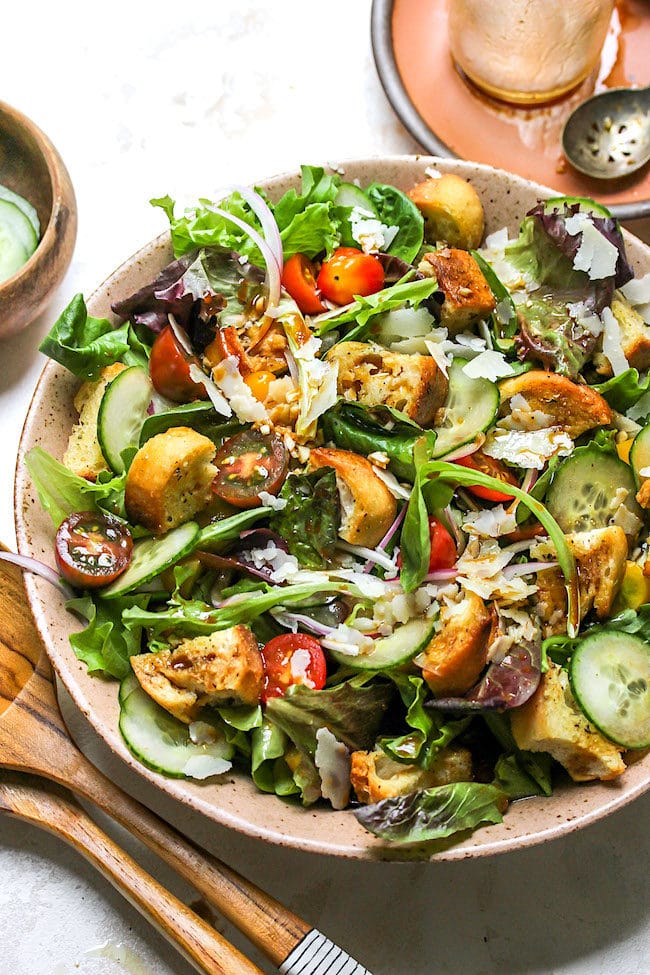 Green Salad in serving bowl topped with homemade croutons, Parmesan cheese, and balsamic vinaigrette.