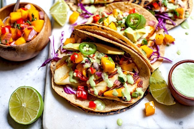 Grilled Halloumi Tacos on marble board with mango salsa in small bowl. 