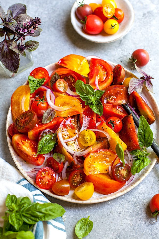 tomato salad with red onion and basil on plate.