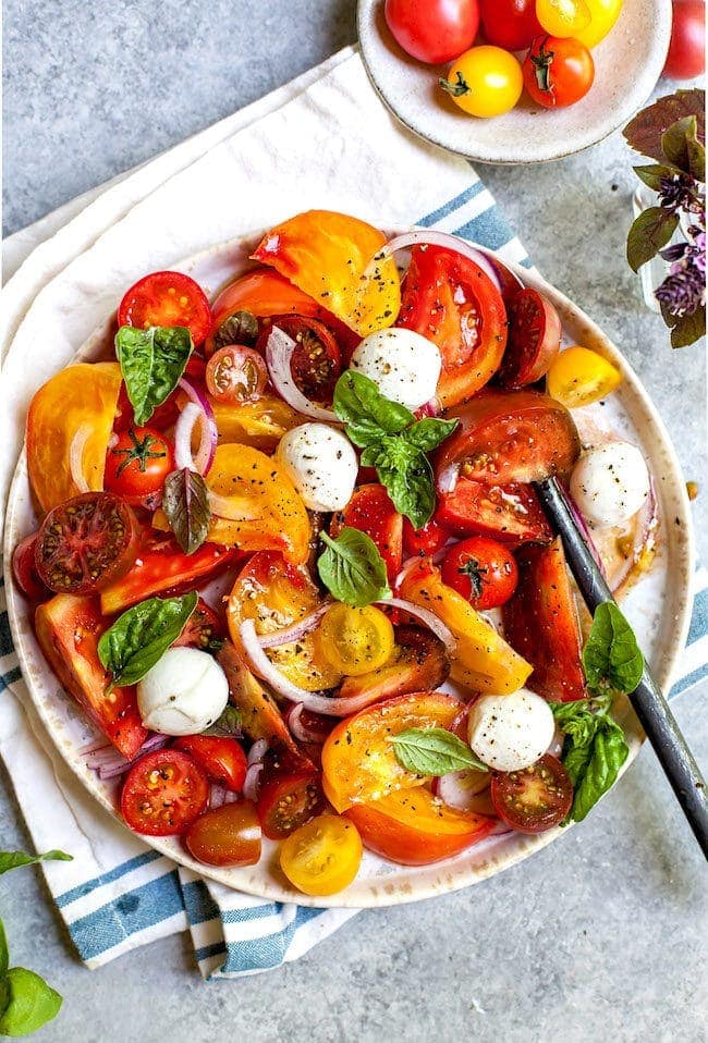 Tomato Salad on plate with mozzarella, basil, and onion.