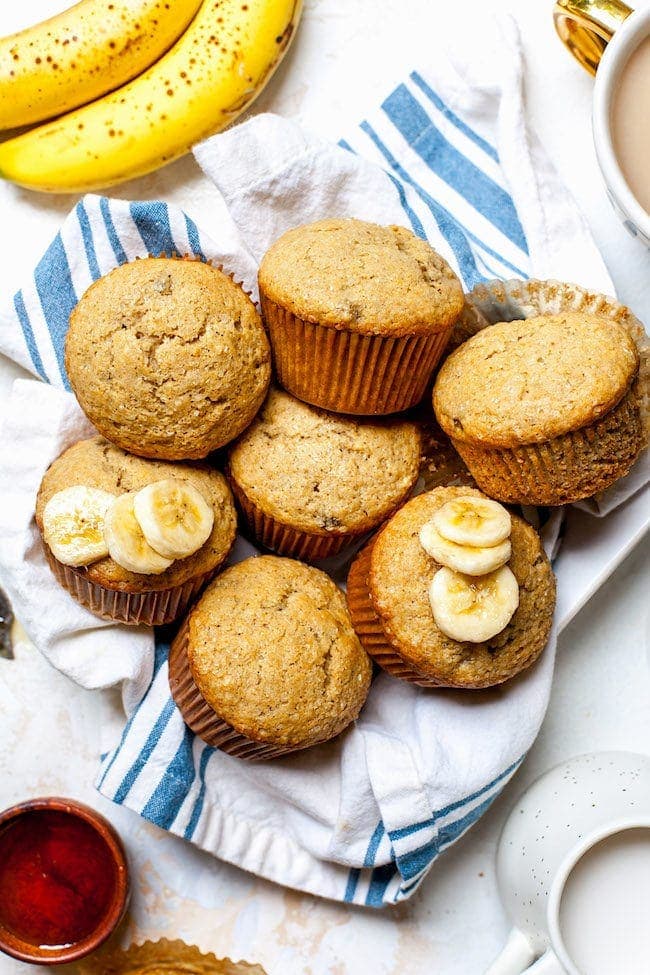 Banana Muffins on platter with tea towel and banana slices. 