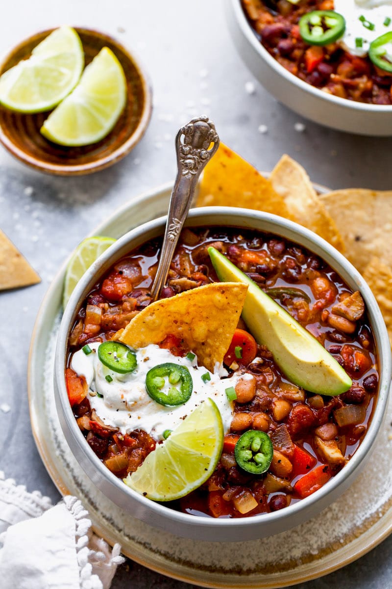 vegetarian chili in bowl with spoon and toppings. 