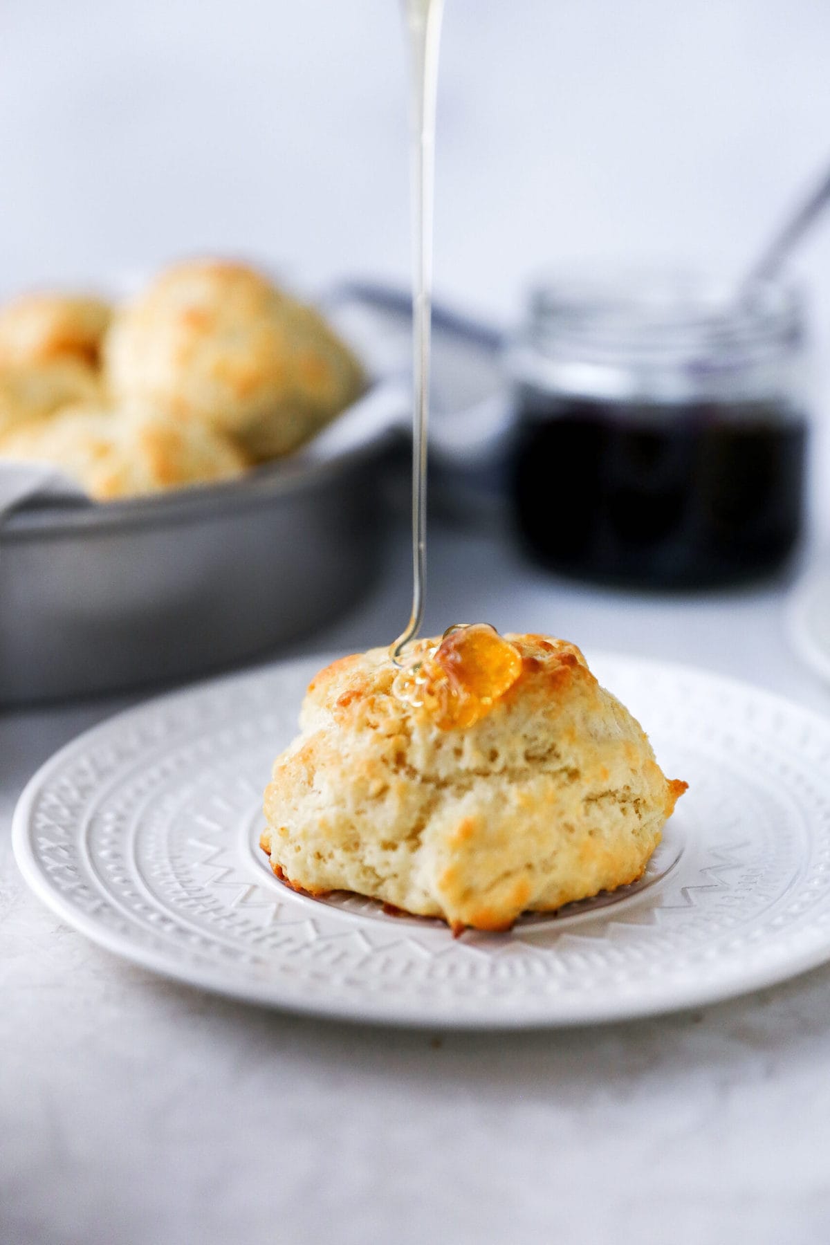 Buttermilk Drop Biscuits on plate with honey being drizzled over the top. 